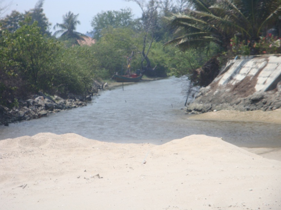 a lake with a little run off across the sand