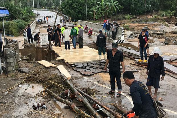 Residents repair the flood-damaged bridge on the main entry road to their village in Bang Saphan district, Prachuap Khiri Khan on Thursday. (Photo by Chaiwat Satyaem)