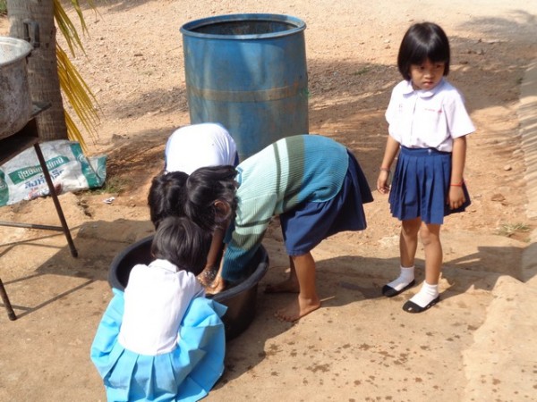 queuing up to wash their hands in a bucket of water