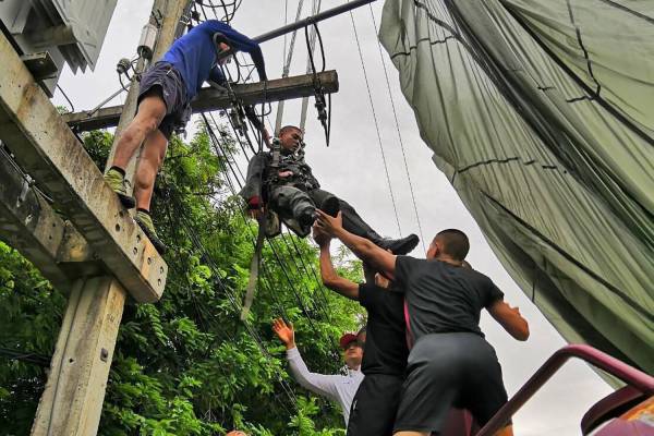 A police team tries to bring Pol L/Cpl Nattakorn Chaikuemkao from the top of an electric pole after his parachute got caught by a transformer on top of it near Naresuan Base in Cha-am district, Prachuap Khiri Kan province, on Friday.