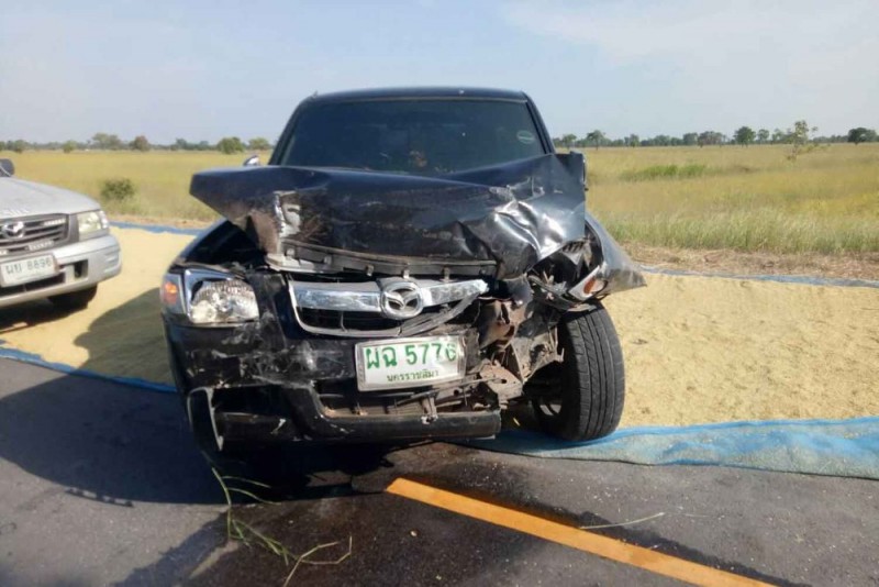 One of three pickup trucks involved in the fatal accident rests on drying paddy which partially blocks the road in tambon Makha of Non Sung district, Nakhon Ratchasima, on Sunday. (Photo by Prasit Tangprasert)