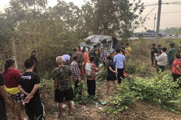 Local residences watch rescue volunteers helping passengers in a van which was overturned in Muang district of Kanchanaburi on Sunday. (Photo by Piyarat Chongcharoen)