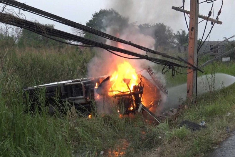 Flames shoot out of a refrigerated truck that caught fire after a tyre burst and it struck a power pole on Phetkasem Road in Pran Buri on Saturday. The driver was burned to death and his wife sustained injuries. (Photo by Chaiwat Satyaem)