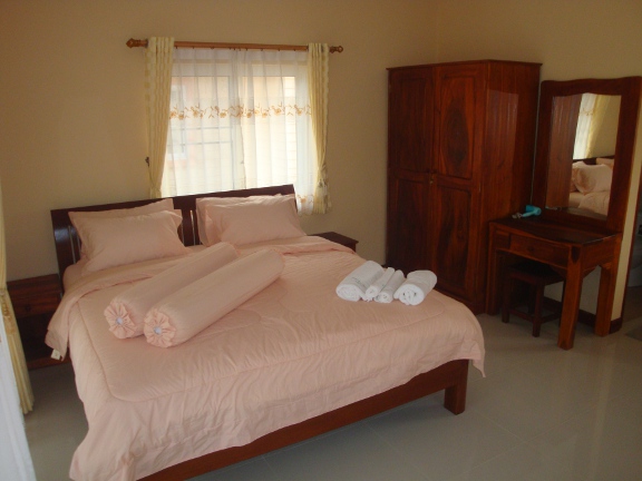 Inside a bungalow looking towards the solid wood bed, wardrobe and dressing table.